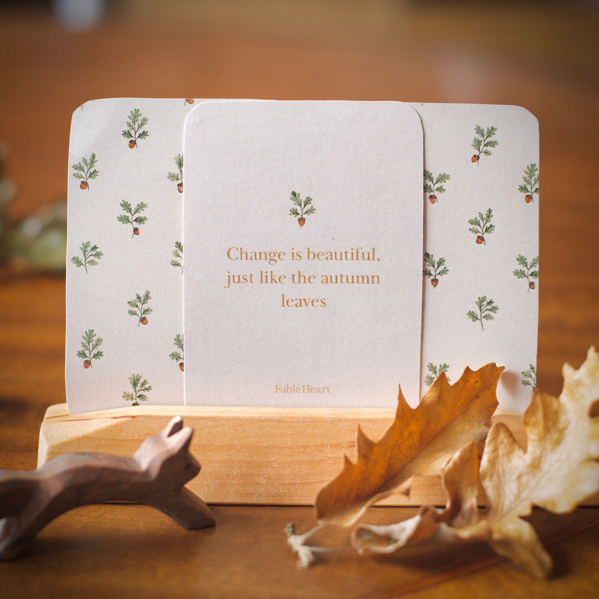 Autumn affirmation card, Change is beautiful just like the autumn leaves, with two acorn-patterned card backs on a wooden stand